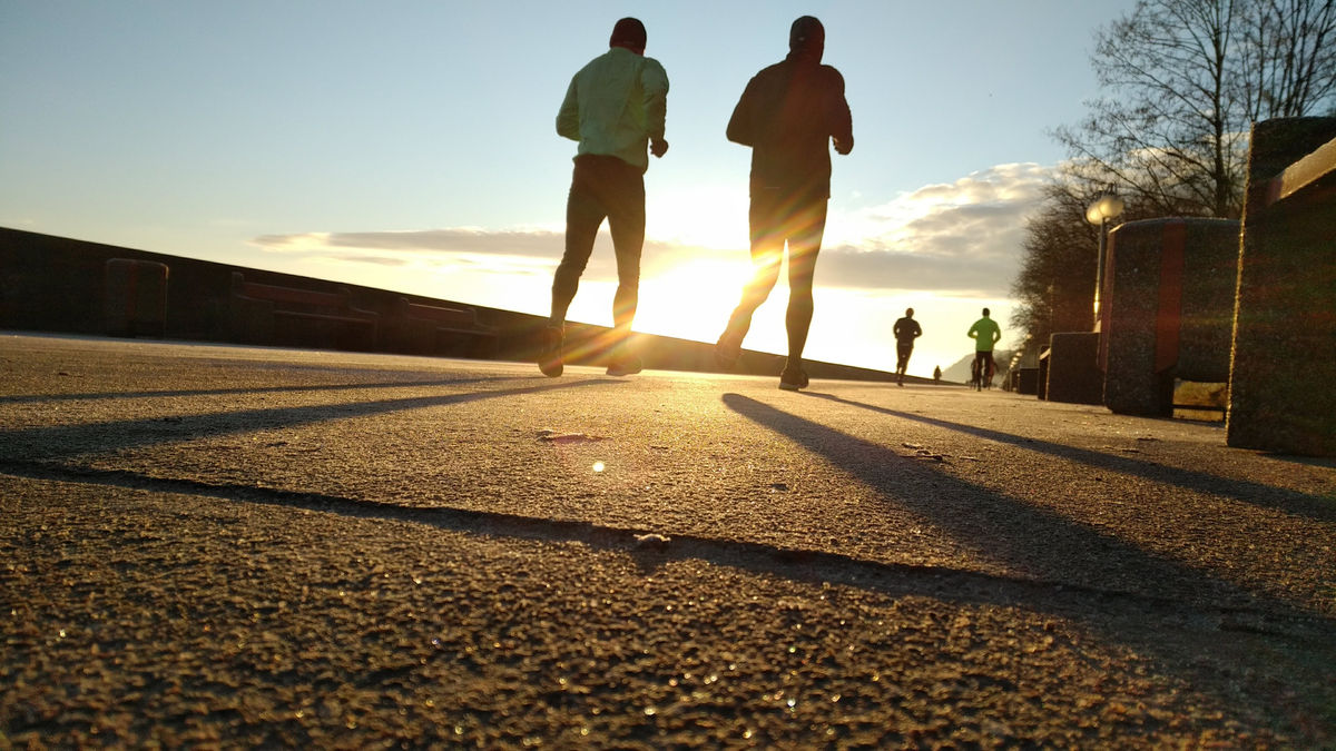 Deux coureurs à contre-jour sur un quai au lever du soleil