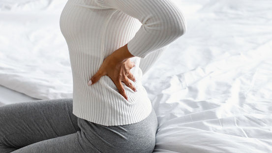 Femme qui se tient le bas du dos à cause d’une douleur lombaire