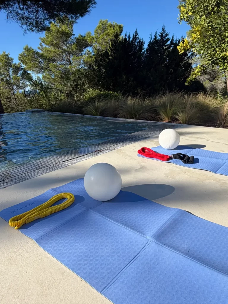 Séance de sport en plein air au bord de la piscine, avec tapis, ballons et élastiques